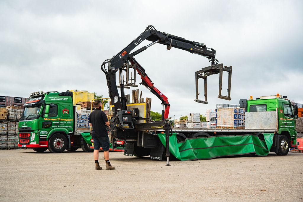 Crane lorry offloading a pallet of bricks